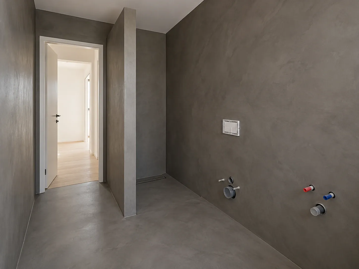 Łazienka z grafitowego mikrocementu z prysznicem walk-in, ściany i podłoga w jednej powierzchni